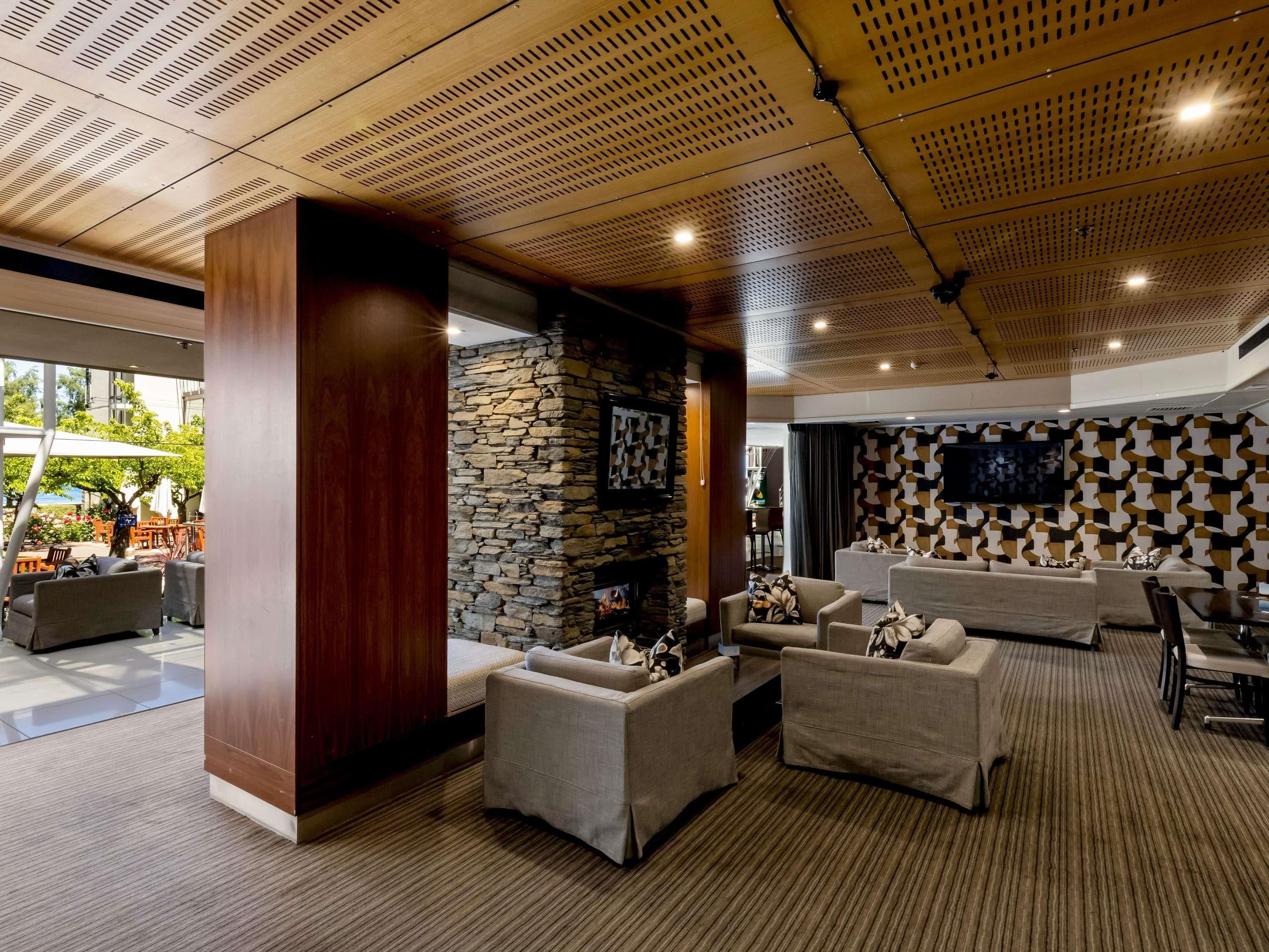 A modern lounge area with sofas, a stone accent wall, and a flat-screen TV.