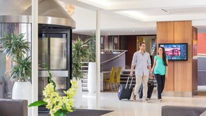 A modern lobby with a reception desk, a digital screen, and a staircase leading to upper floors. - Novotel Queenstown Lakeside (Queenstown)