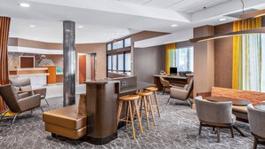 Een moderne hotel lobby met een receptiebalie, een zithoek en een bar.