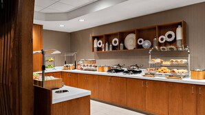 Een moderne keuken met houten kastjes, een wit aanrechtblad en diverse etenswaren.