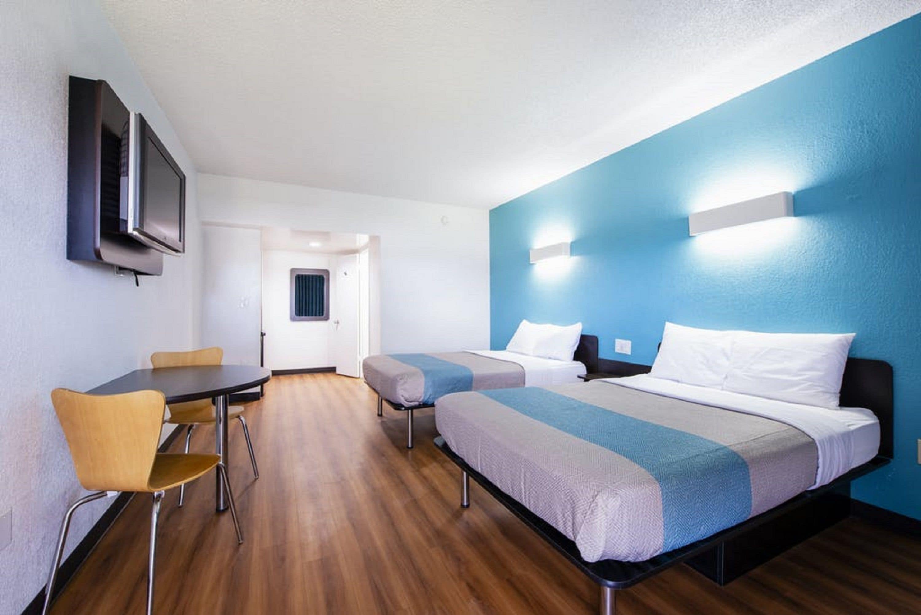 A hotel room with two beds, a desk, and a TV.
