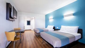 A hotel room with two beds, a desk, and a TV.