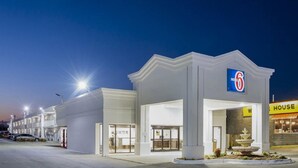 A motel with a prominent '6' sign, a fountain, and a 'House' sign nearby. - Motel 6 Jacksonville, NC (Jacksonville)