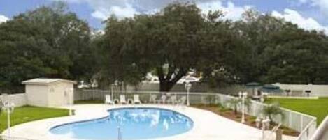 A swimming pool with a white deck and a fence.