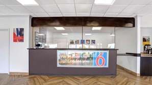 A reception desk with a sign that reads "We'll leave the light on for you." - Motel 6 Jacksonville, NC (Jacksonville)
