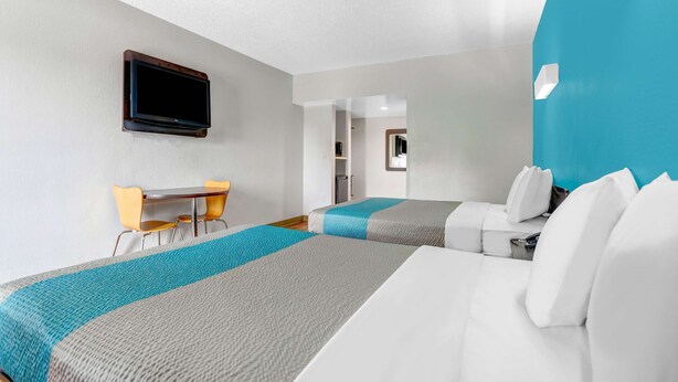 A hotel room with two beds, a desk, and a television mounted on the wall. - Motel 6 Jacksonville, NC (Jacksonville)