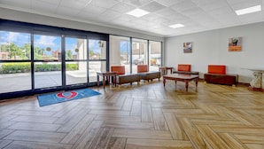 A spacious lobby with a herringbone wood floor, large windows, and modern furniture. - Motel 6 Jacksonville, NC (Jacksonville)