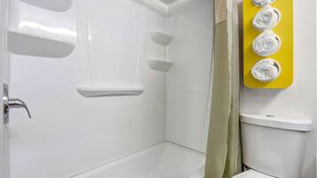 A bathroom with a bathtub, a toilet, and a towel rack with four towels.