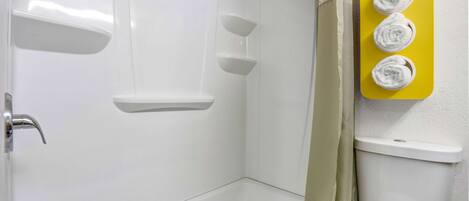 A bathroom with a bathtub, a toilet, and a towel rack with four towels.