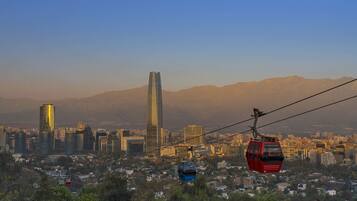 Un sistema de teleférico con un paisaje urbano de fondo, que incluye un rascacielos destacado.