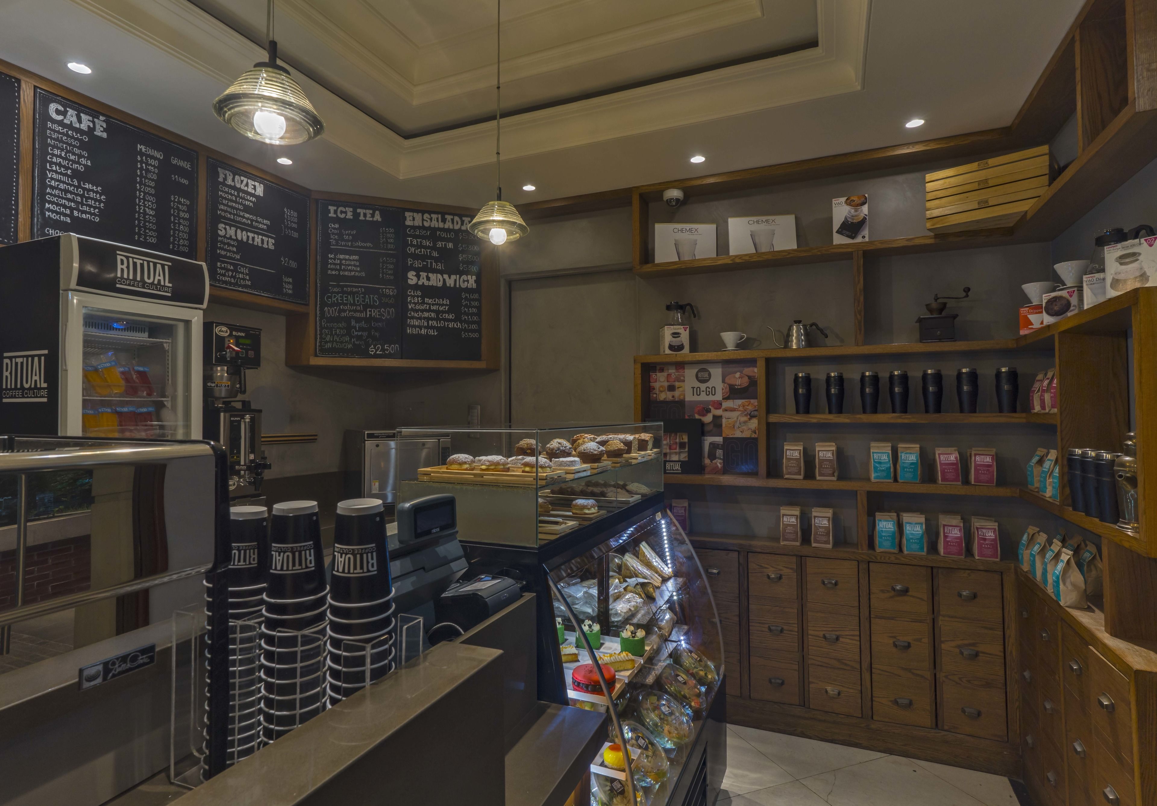 Un interno di una caffetteria con una macchina da caffè, menù esposti e una vetrina con dolci.