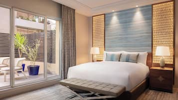 A hotel room with a bed, a bench, a window with a view, and a wall with a geometric pattern.