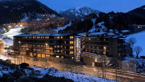 Un hôtel à plusieurs étages, doté d’une architecture moderne, situé dans une région montagneuse aux alentours enneigés.