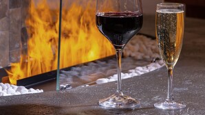 Un coin bar avec une cheminée, deux verres de vin et un comptoir.