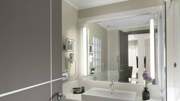 A modern bathroom with a large mirror, a white sink, and a glass shower enclosure.