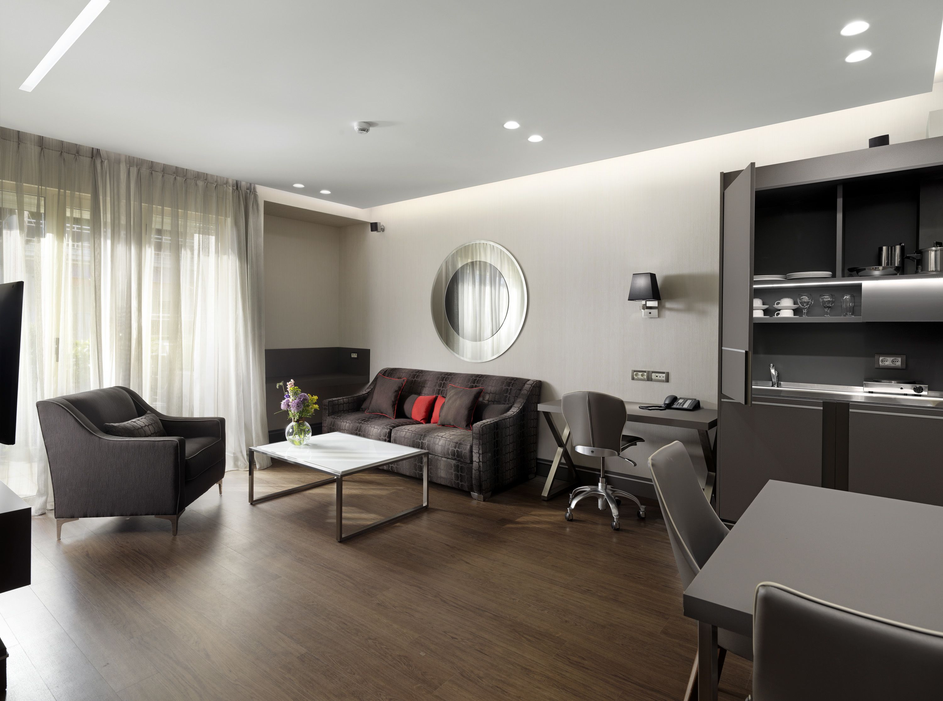 A modern living room with a sofa, armchairs, a coffee table, and a dining area.