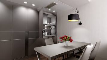 Una cocina moderna con zona de comedor, con una mesa larga, sillas, un florero con flores rojas y una lámpara colgante.