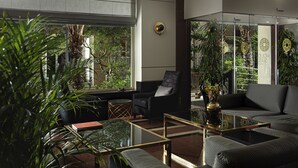 Un hall d’hôtel moderne, doté d’un espace salon, d’une paroi en verre et offrant une vue sur l’extérieur.
