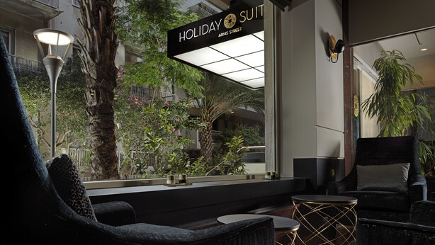 Un hall d’hôtel moderne doté d’un comptoir d’accueil, d’un espace salon et offrant une vue sur l’extérieur.