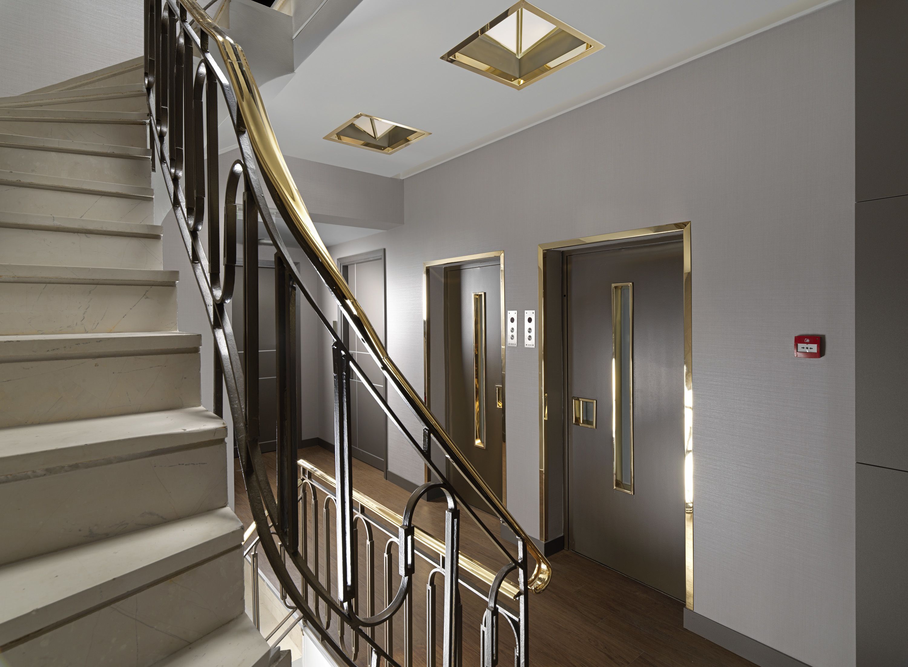 A modern interior with a staircase, a door with a mirror, and a light fixture on the ceiling.