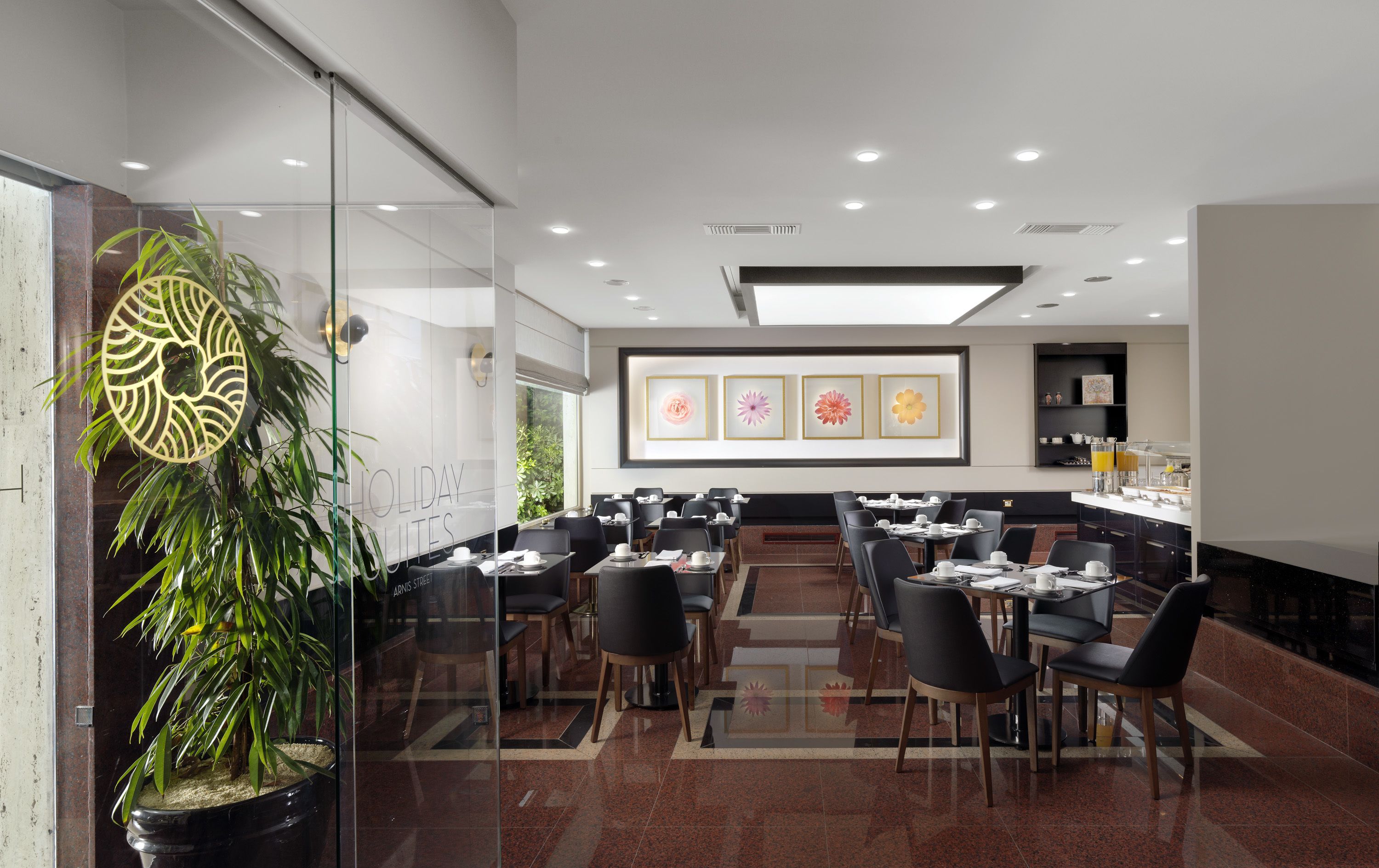 A modern hotel lobby with a glass wall, a potted plant, and a reception desk.