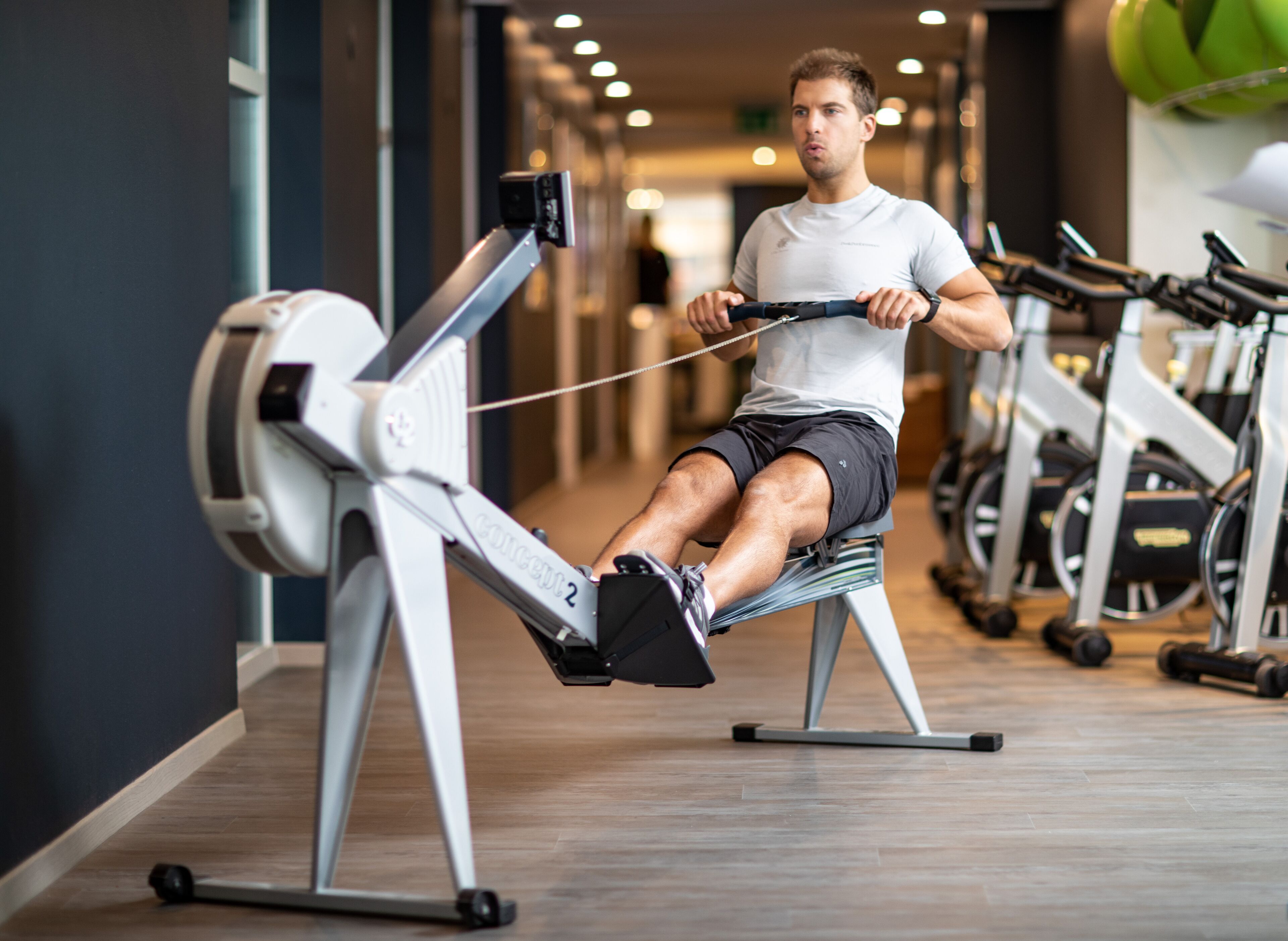 Et fitnesscenter med træningsudstyr, heriblandt en romaskine og spinningcykler.