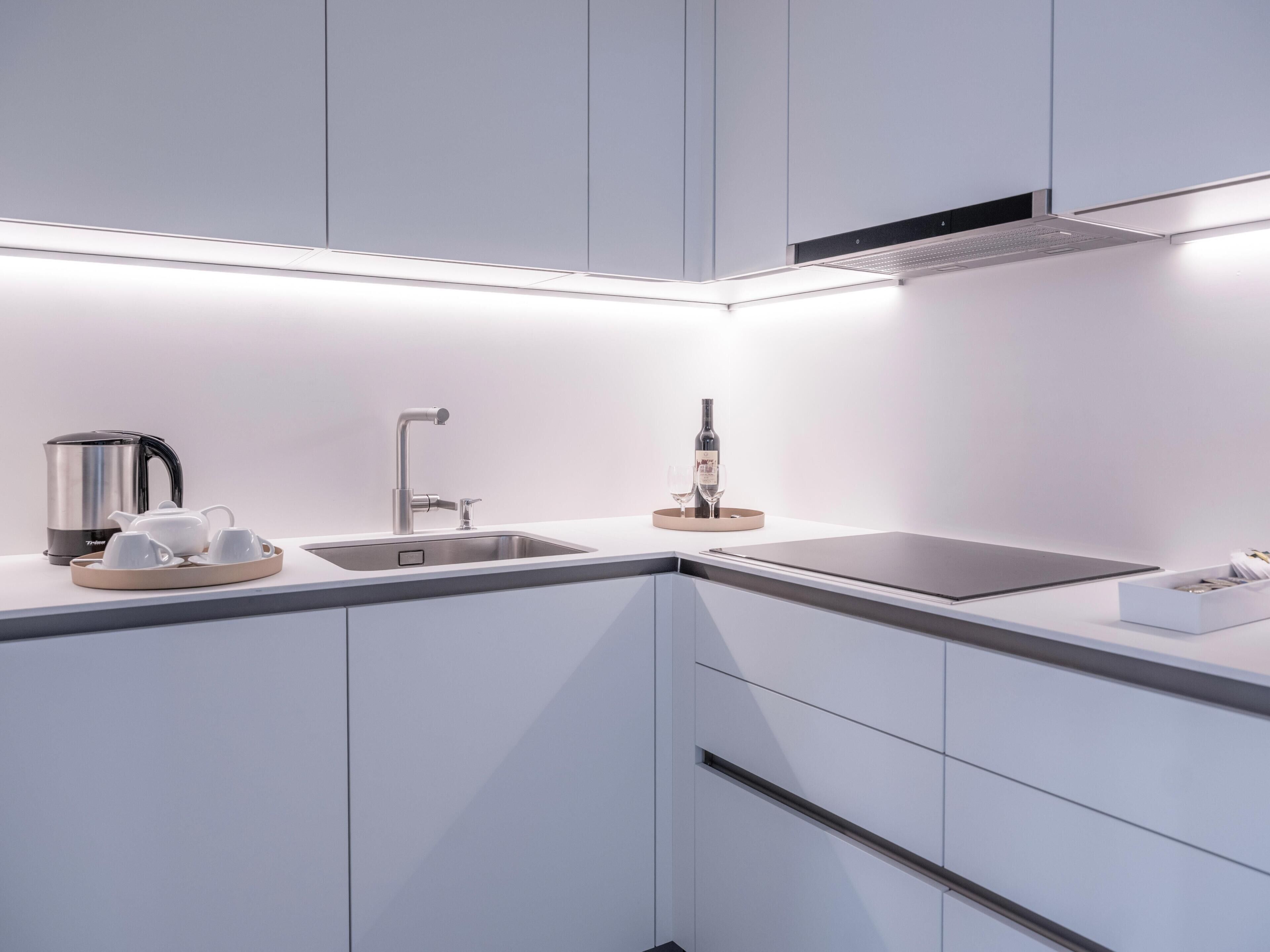 Una cocina moderna con un lavamanos de acero inoxidable, un hervidor y una botella de vino sobre la encimera.