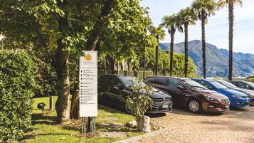 A parking area with several cars, a sign listing amenities, and a mountainous backdrop.