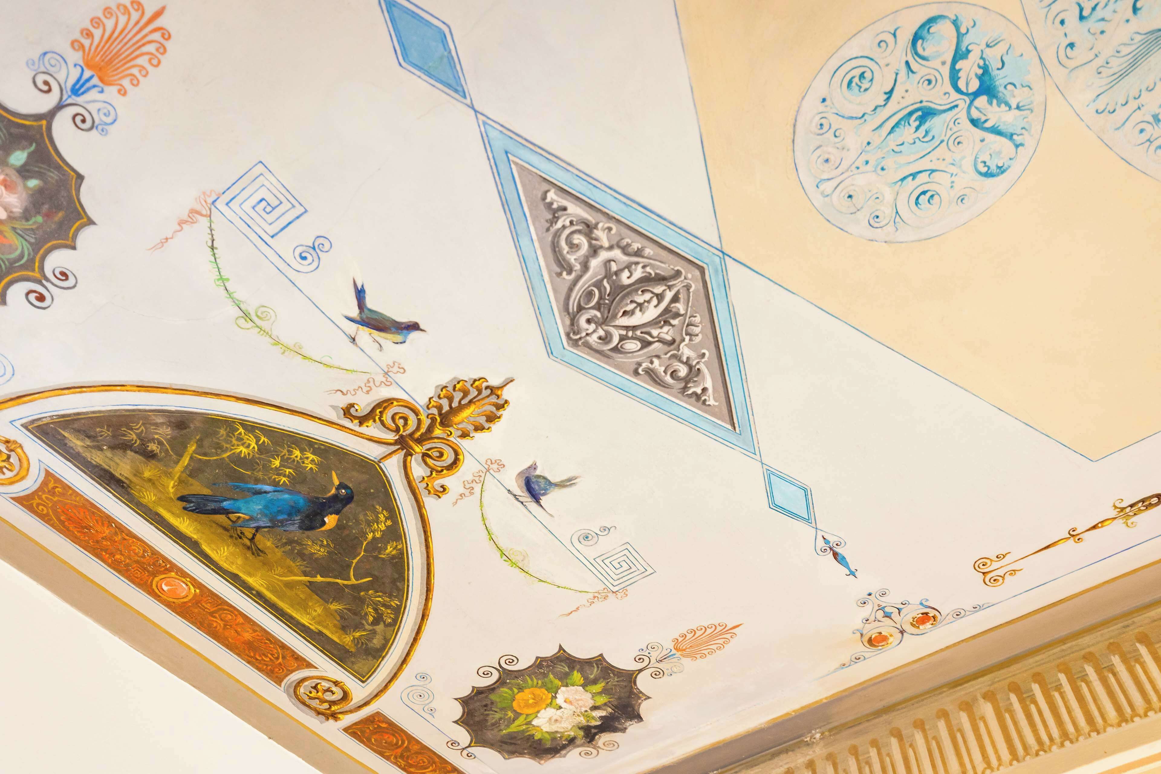 A ceiling with ornate designs, including birds and floral patterns.