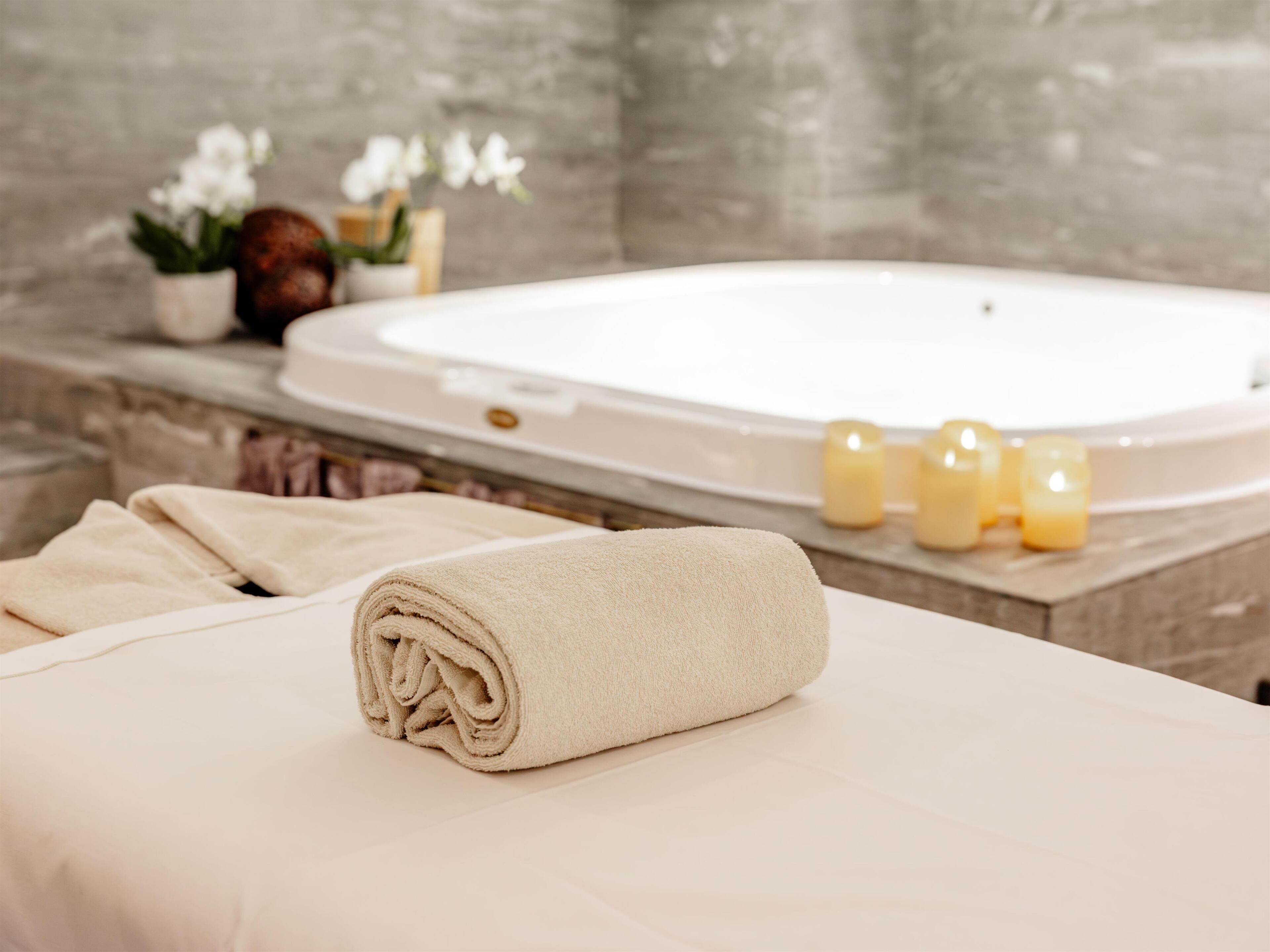 A spa area with a bathtub, candles, and towels.