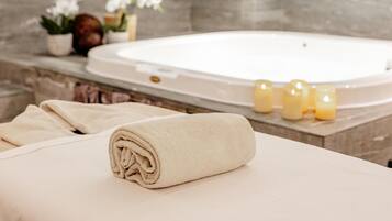 A spa area with a bathtub, candles, and towels.