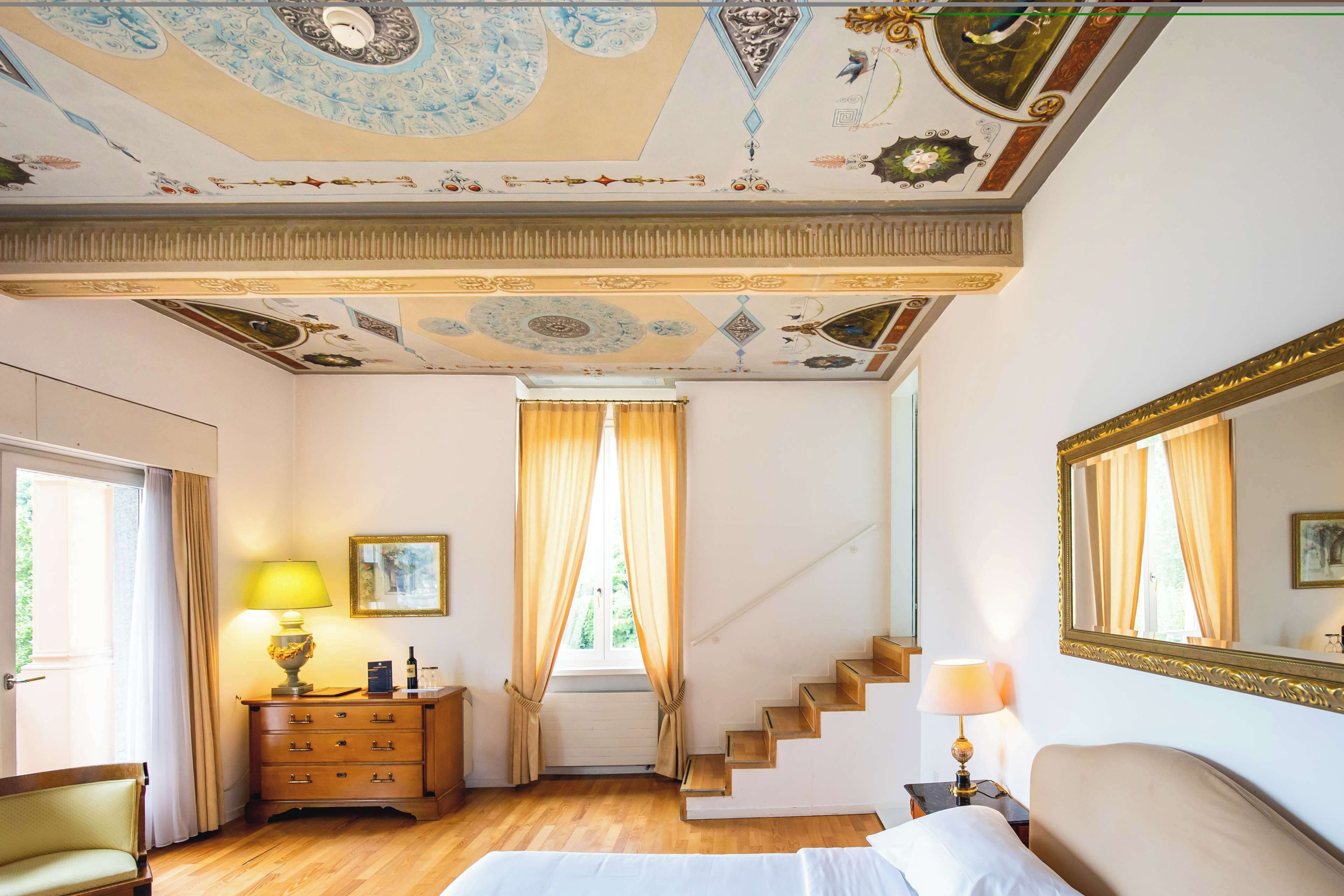 Ein Hotelzimmer mit einer Holztreppe, einem Bett, einem Schminktisch, einer Lampe und einem großen Spiegel.
