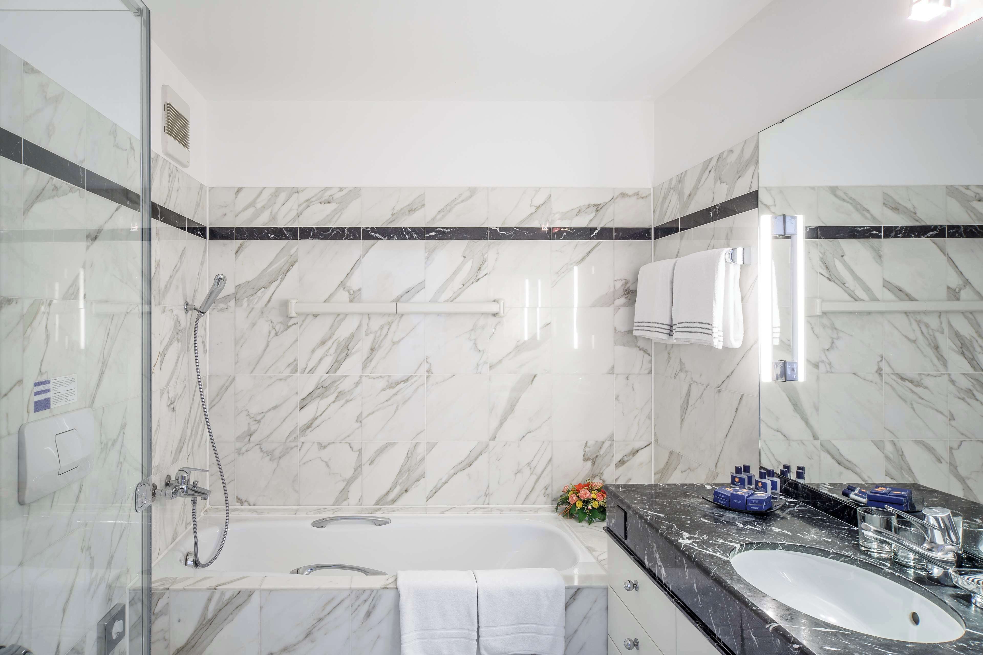 A modern bathroom with a glass-enclosed shower, a freestanding bathtub, and a vanity with a sink and mirror.