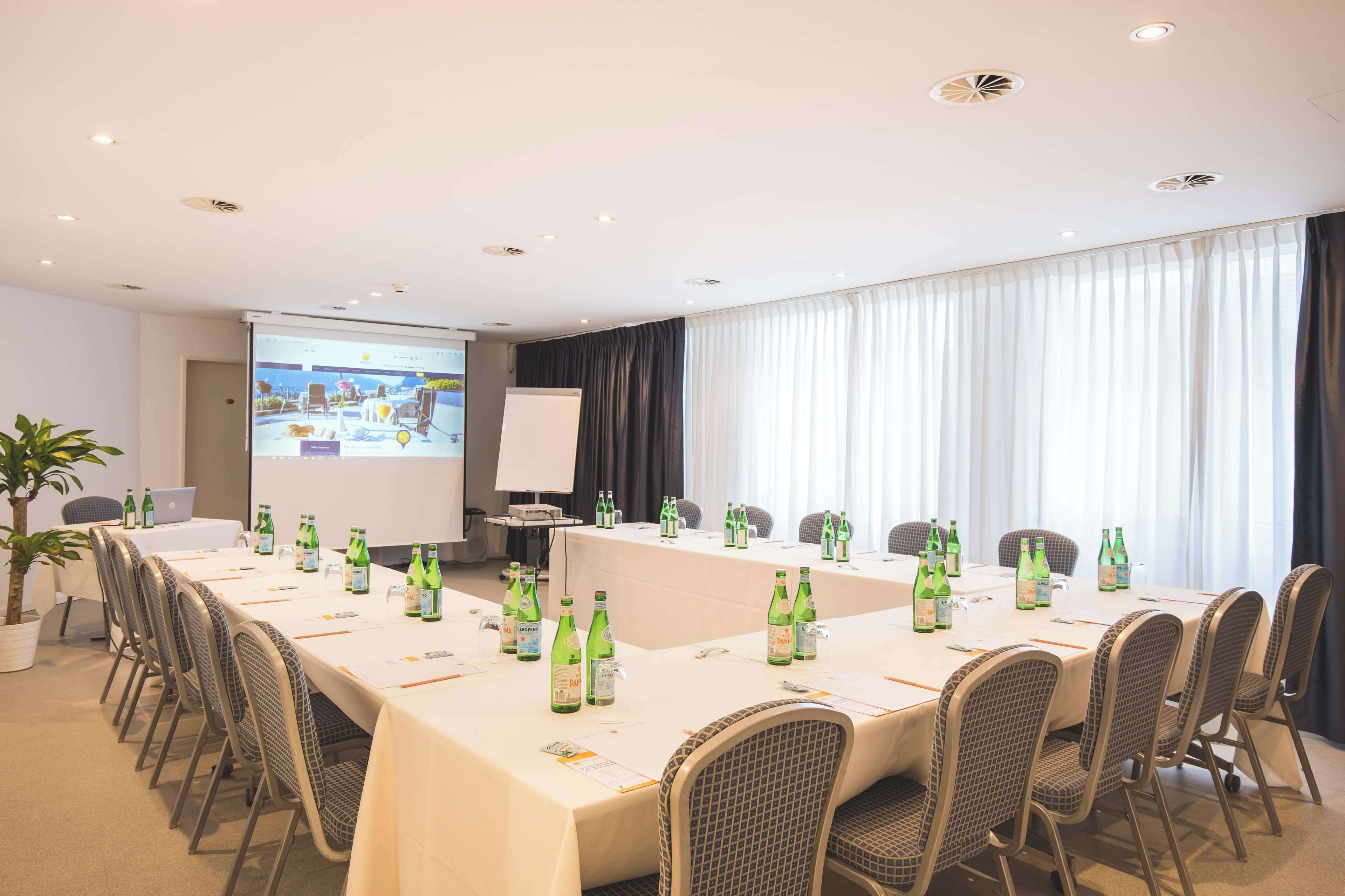 A conference room with a long table, chairs, and a projector screen.