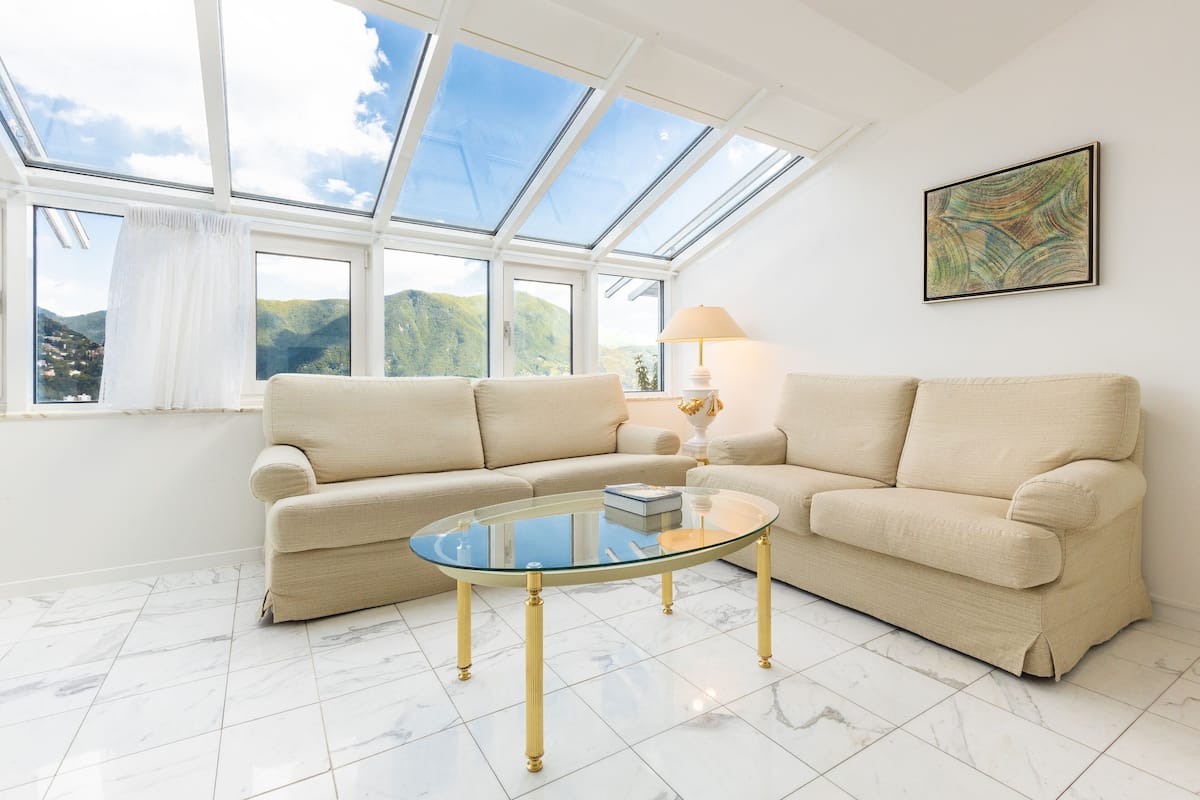 A living room with a glass coffee table, beige sofas, a lamp, and a painting on the wall.