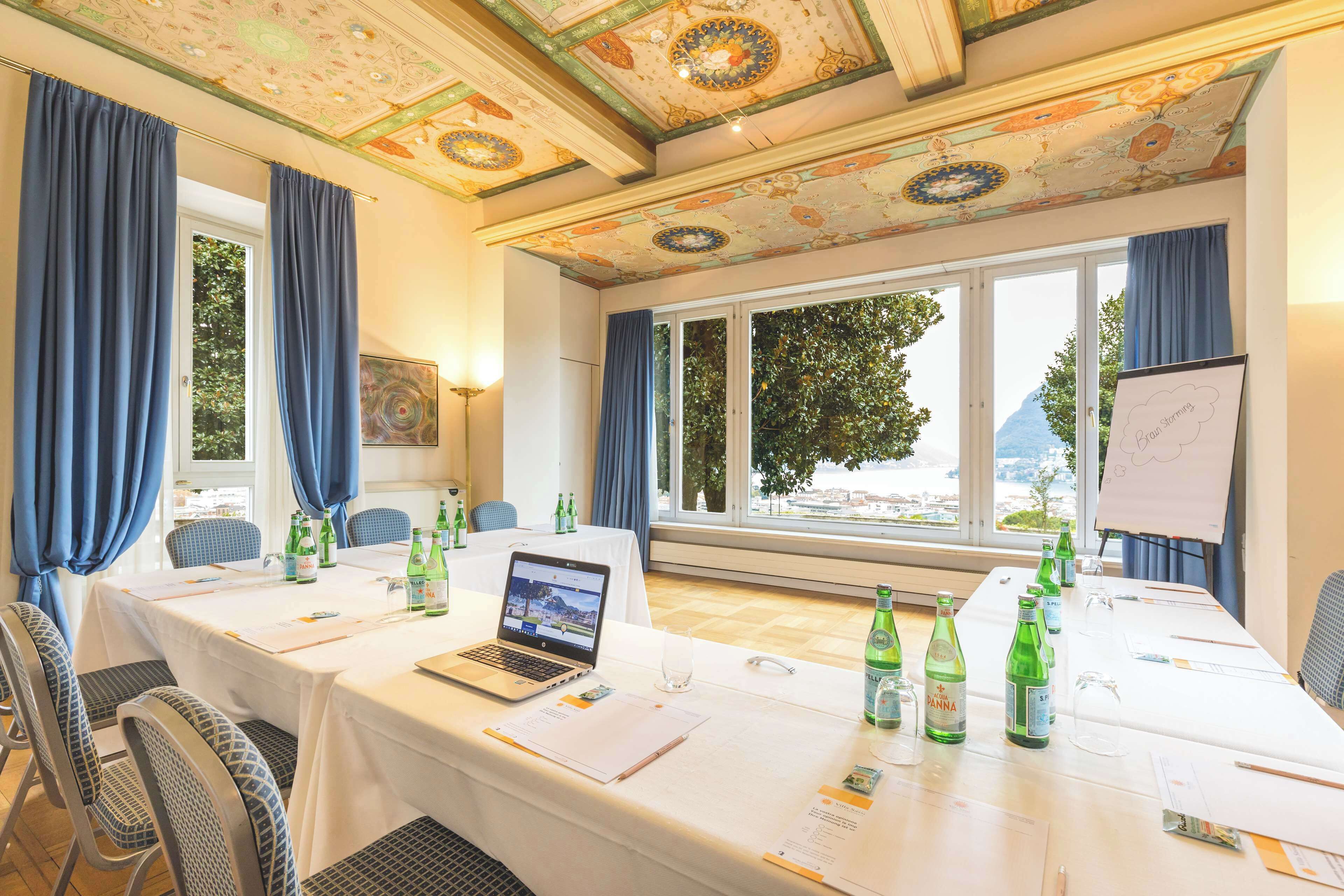 A conference room with a table set for a meeting, a laptop, and documents.
