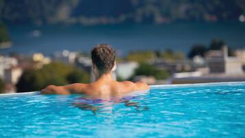 A person relaxing in a clear blue pool with a mountainous backdrop.