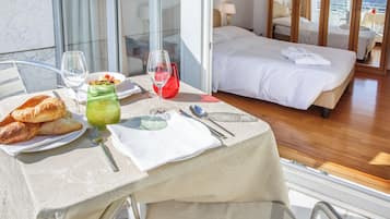 Ein Hotelzimmer mit einem Bett, einem Esstisch mit Frühstück und Blick auf die Stadt.
