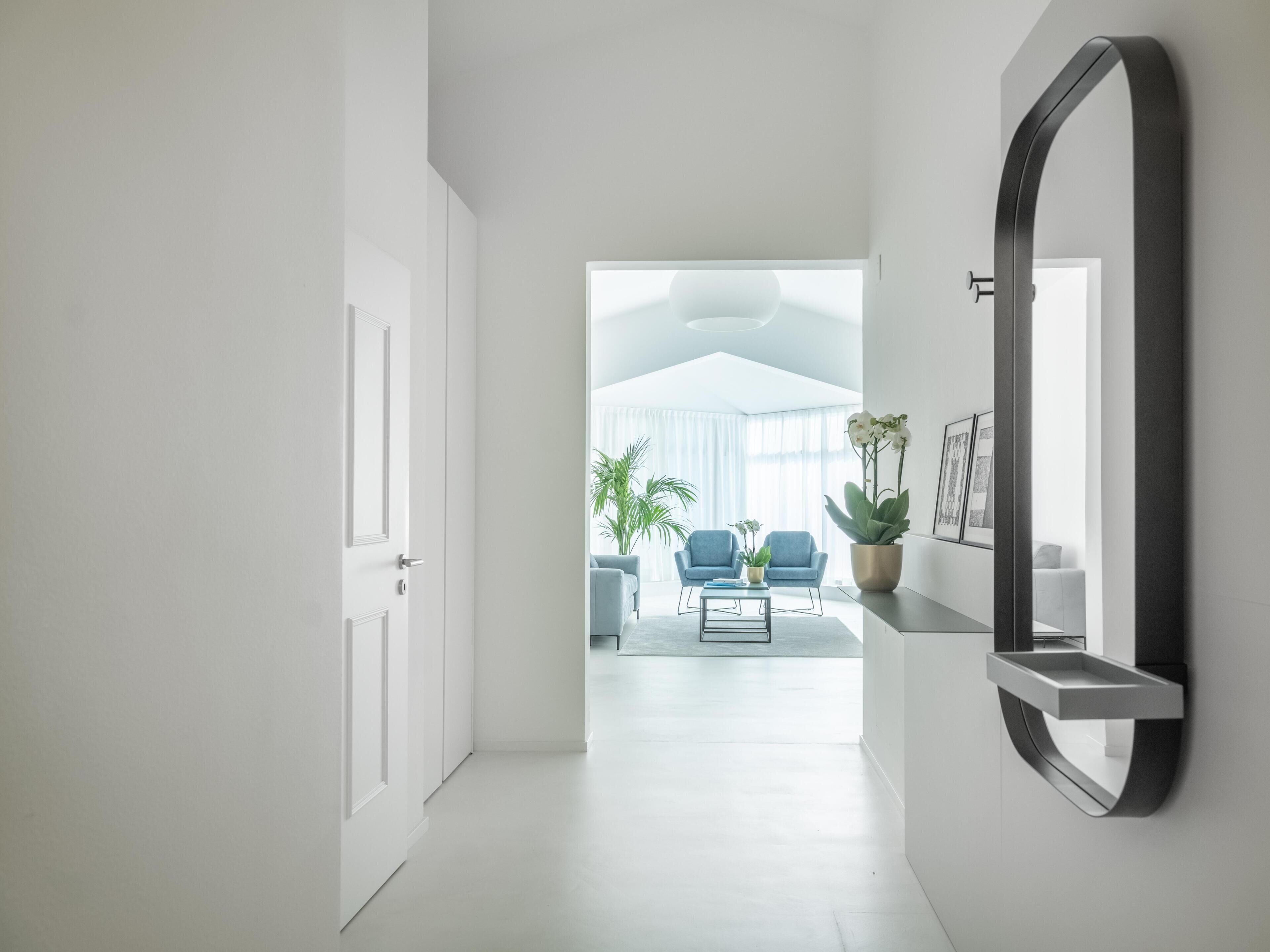 A hallway leading to a living area with a large mirror, a sofa, and a coffee table.