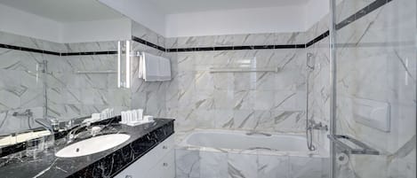 Een moderne badkamer met een zwart marmeren aanrechtblad, een wit wastafelmeubel, een douche met glazen wanden en een wit toilet.