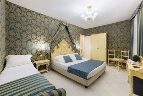 A bedroom with a large bed, a smaller bed, a nightstand, a dresser, and a chair. - Hotel San Giorgio (Venice)