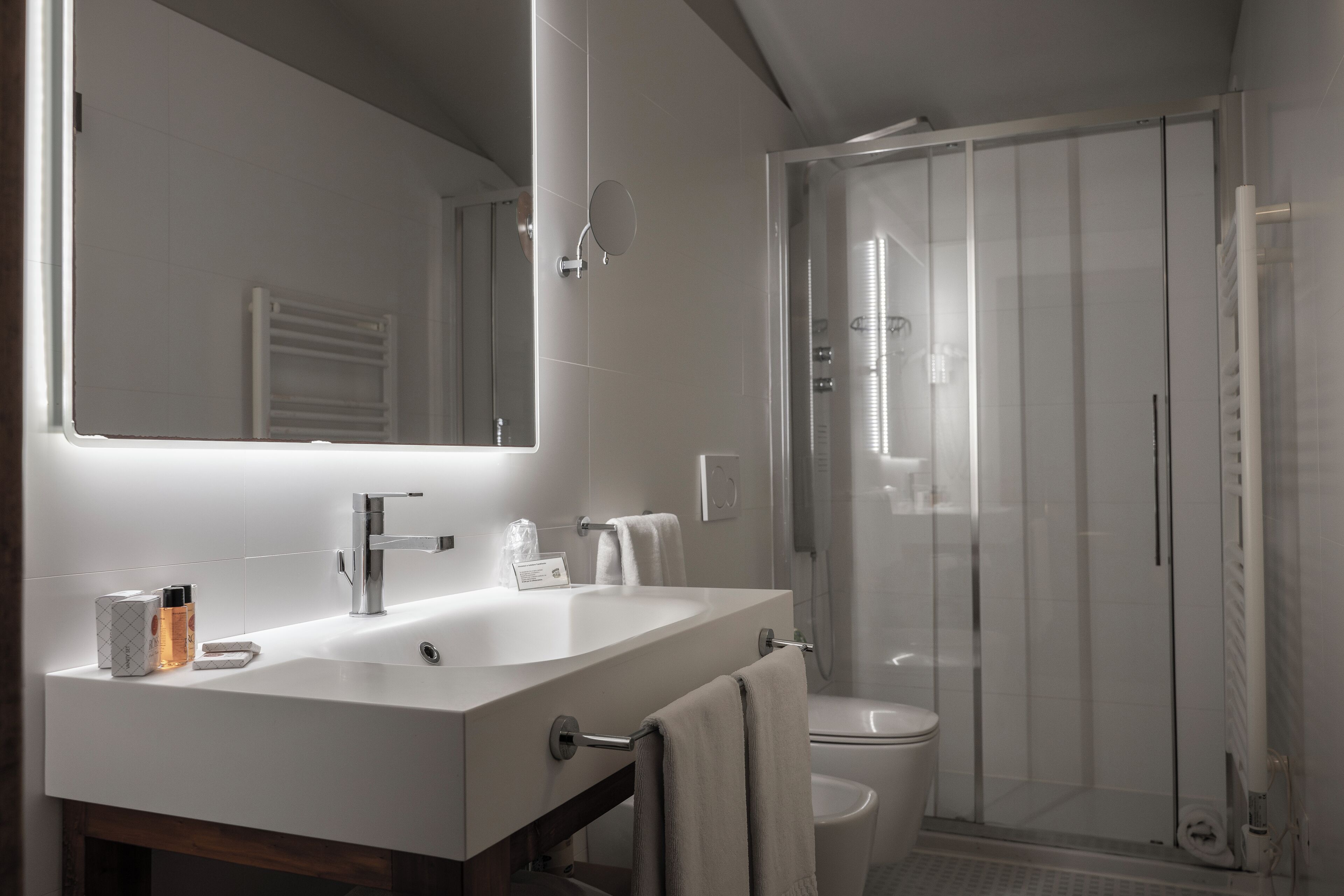 A modern bathroom with a large mirror, a sink, and a shower enclosure.
