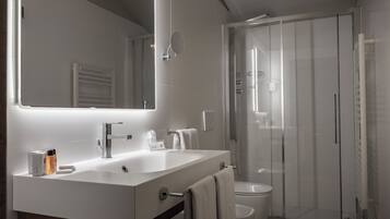A modern bathroom with a large mirror, a sink, and a shower enclosure.