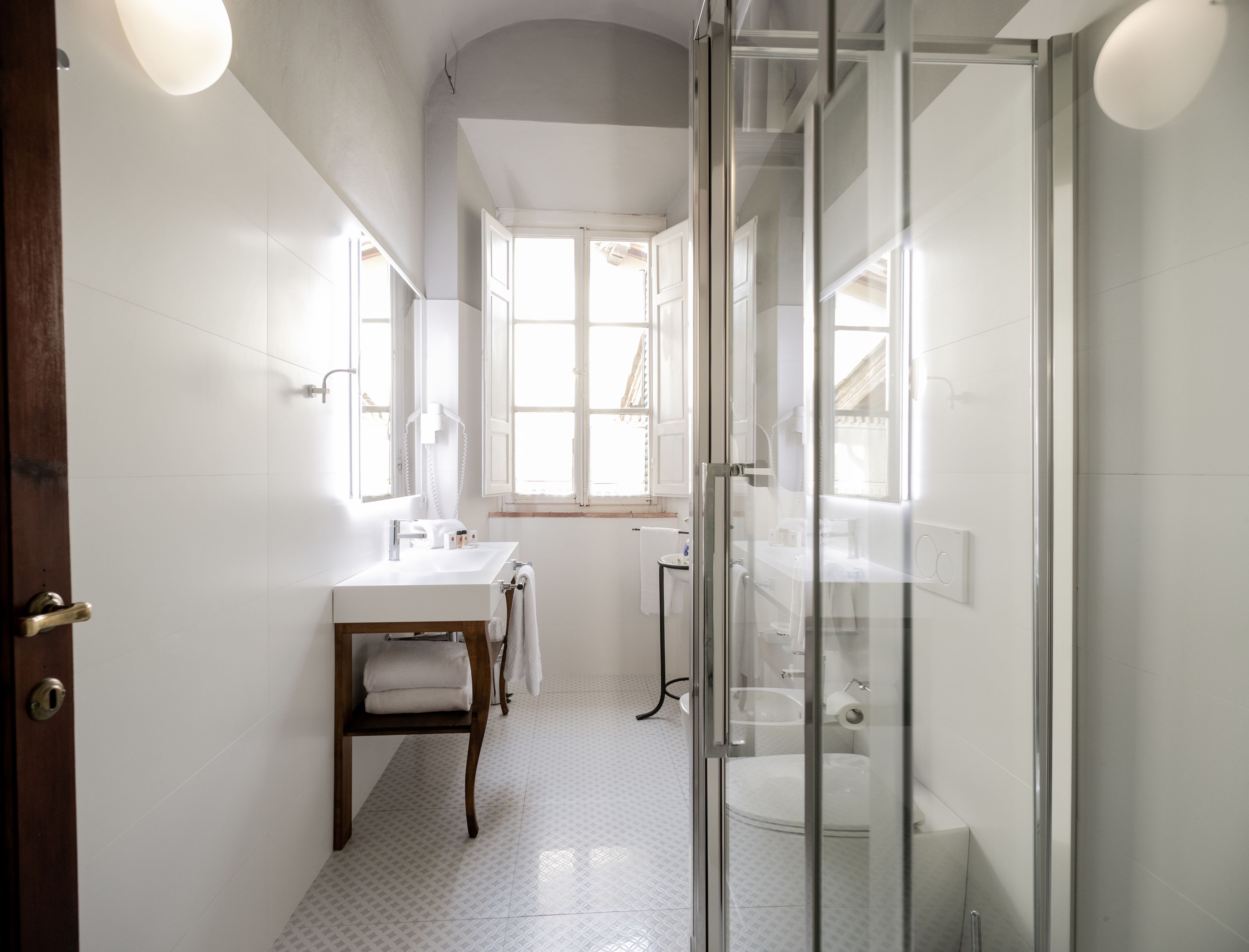 A modern bathroom with a glass shower enclosure, a white sink, and a wooden vanity.
