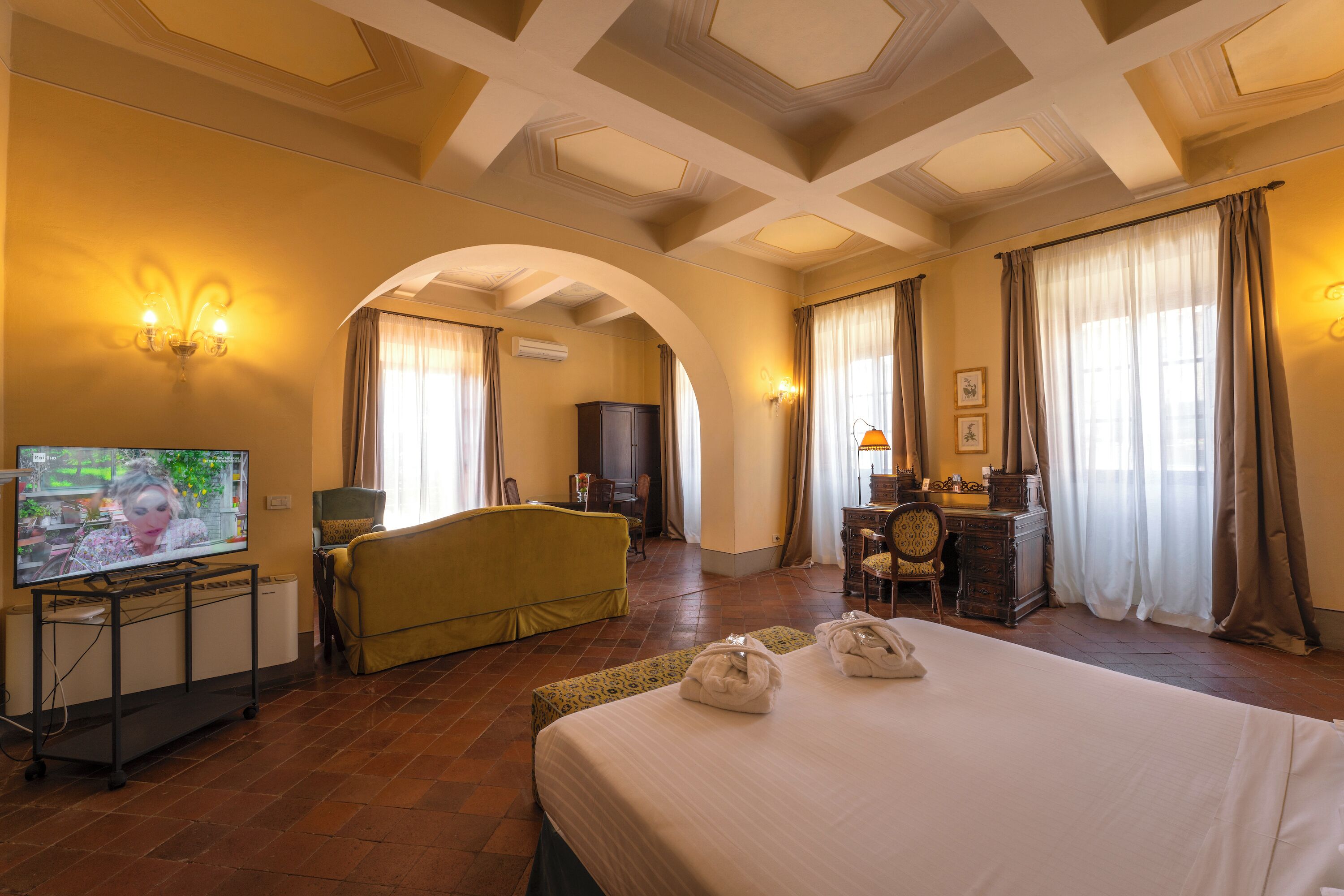 Une chambre d’hôtel avec un grand lit, une télévision, un bureau avec une chaise et un canapé.