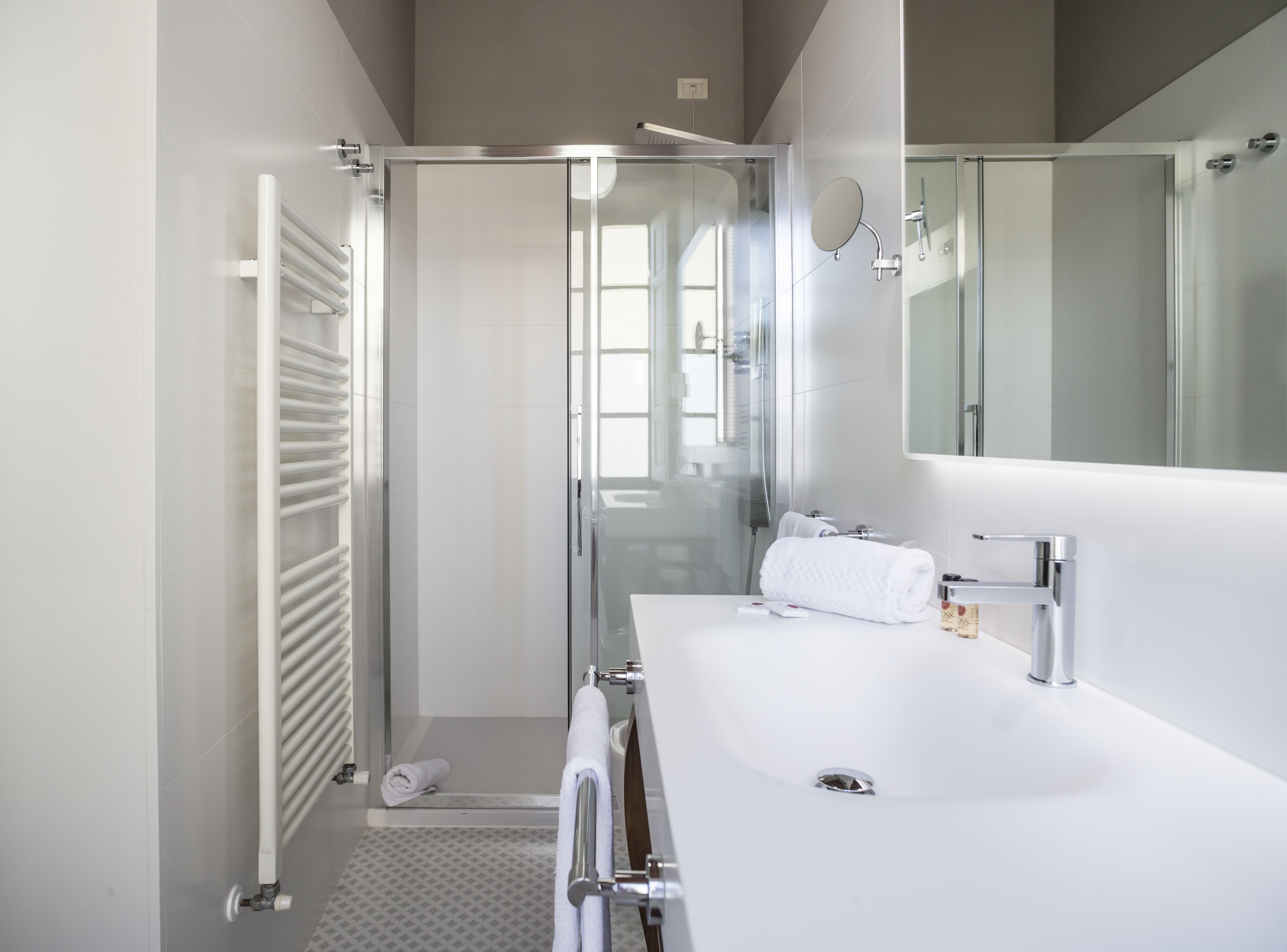 A modern bathroom with a glass shower enclosure, a white sink, and a large mirror.