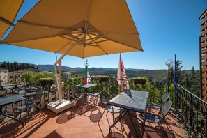 A terrace with outdoor seating, a large umbrella, and a view of the countryside. - Palazzo Leopoldo Dimora Storica & Spa (Radda in Chianti)