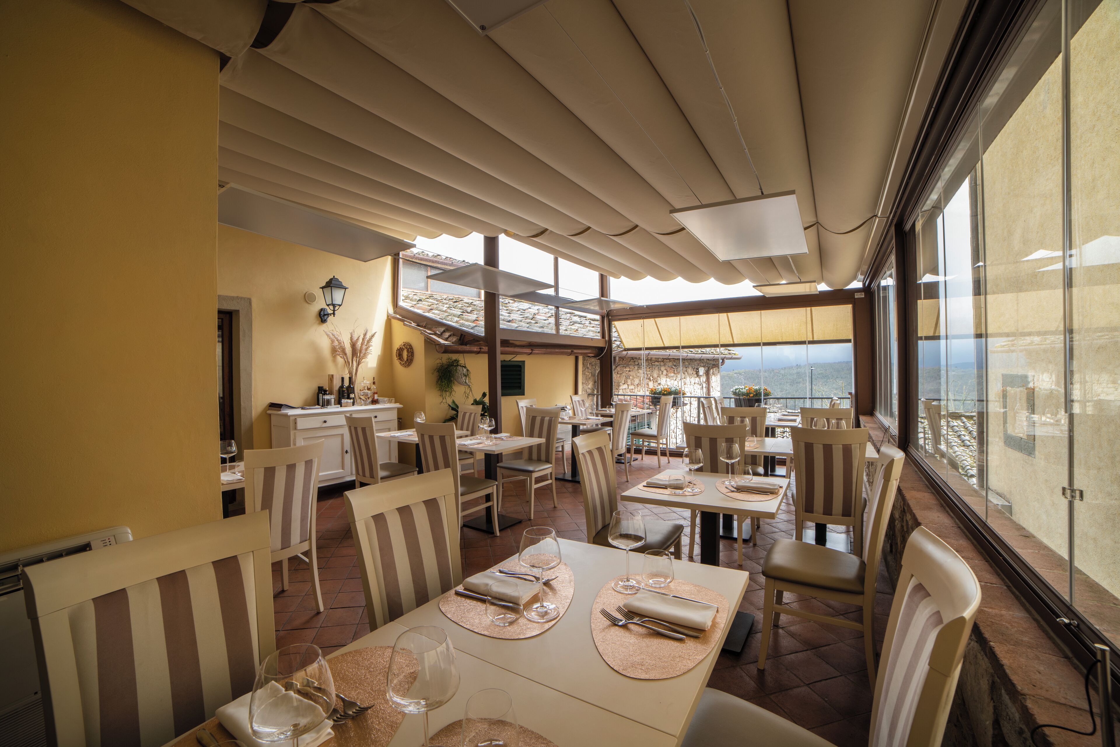 Un restaurant avec des tables dressées, des chaises et une vue sur la mer.
