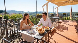 A couple dining at an outdoor table with a view of the countryside. - Palazzo Leopoldo Dimora Storica & Spa (Radda in Chianti)