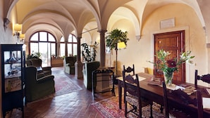 A spacious room with high arched ceilings, a wooden dining table, chairs, and a bookshelf. - Palazzo Leopoldo Dimora Storica & Spa (Radda in Chianti)